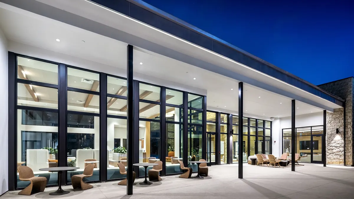 The clubhouse at dusk, its glass rooms lit.