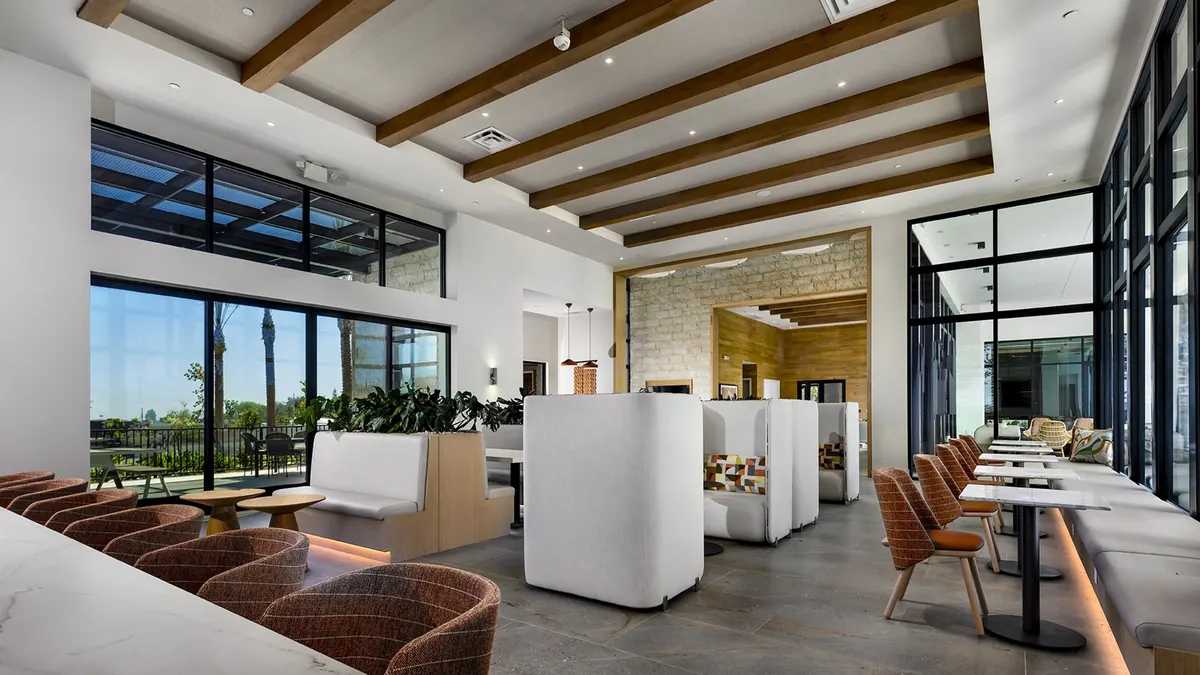 The clubhouse lounge in the evening, chairs around a long table, the windows going blue.